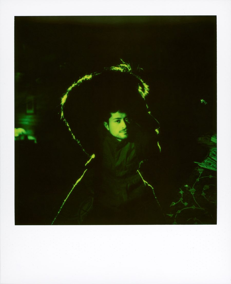 Polaroid casi negra de un retrato con el contorno iluminado en verde